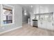 Open concept kitchen and stairway featuring white cabinets, stainless steel appliances, and hardwood floors at 10778 Dayton Way, Commerce City, CO 80640