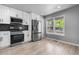 Bright kitchen featuring stainless steel appliances, white cabinets, modern countertops, and hardwood floors at 10778 Dayton Way, Commerce City, CO 80640