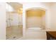 Bright bathroom featuring a soaking tub under an arched alcove and a glass-enclosed shower at 8100 E Union Ave # 2201, Denver, CO 80237