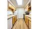 Galley kitchen with wood cabinets, white appliances, and updated laminate flooring at 9262 E Arbor Cir # H, Englewood, CO 80111