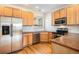 Well-lit kitchen with wood cabinets, stainless steel appliances, and wood flooring at 755 Roslyn St # 17, Denver, CO 80230