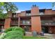 Exterior shot of multi-level condo with balconies, brown siding and green landscaping at 451 Wright St # 11, Lakewood, CO 80228