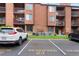 Exterior of brown condo building with parking spots, green grass and air conditioners at 451 Wright St # 11, Lakewood, CO 80228