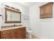 Bathroom features a wood vanity with granite countertop, a toilet, and wall storage cabinet at 15455 Canyon Rim Dr # 304, Englewood, CO 80112