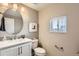 Modern half-bathroom with updated fixtures, a round mirror, and a neutral color palette at 9023 E Northfield Blvd, Denver, CO 80238