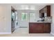 Well-lit kitchen includes stainless refrigerator, stacked laundry machines, granite counters, and oak cabinets at 4812 W 8Th Ave, Denver, CO 80204