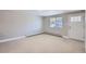 Empty living room showcasing neutral carpet, baseboard heat, large window, and exterior door at 4812 W 8Th Ave, Denver, CO 80204