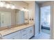 Bright bathroom featuring double sinks with white cabinets and view into bedroom at 1345 W 67Th Pl, Denver, CO 80221