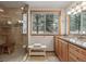 Bathroom featuring a glass enclosed shower, tiled floors, double vanity with granite counter, and wooded views at 2857 Hiwan Dr, Evergreen, CO 80439
