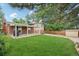 Expansive backyard with lush green lawn, covered patio, shed, and mature trees providing ample shade at 6320 E Asbury Ave, Denver, CO 80224
