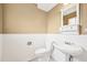 This powder room features a pedestal sink, toilet, decorative mirror and wainscotting at 6320 E Asbury Ave, Denver, CO 80224