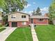 Charming two-story home with a brick facade, a well-manicured lawn, and a paved walkway leading to the front entrance at 6320 E Asbury Ave, Denver, CO 80224