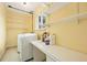 Bright laundry room with yellow walls, storage shelves, counter space, and a washing machine at 6320 E Asbury Ave, Denver, CO 80224