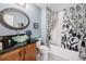 A bathroom with a black countertop, patterned shower curtain, and oval mirror at 860 Bristle Pine Cir # A, Highlands Ranch, CO 80129