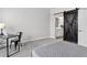 Bedroom featuring a sliding barn door to the bathroom, a plush bed, and a workspace at 19629 W 93Rd Dr # C, Arvada, CO 80007