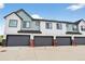 Townhome garages with doors, red posts, and white-and-blue facade at 19629 W 93Rd Dr # C, Arvada, CO 80007