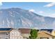 View of mountain with trees and low clouds, behind neighborhood rooftops with solar panels at 19629 W 93Rd Dr # C, Arvada, CO 80007
