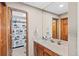 Bathroom with a wood vanity, shower with decorative curtains, and a large mirror at 7624 S Cove Cir, Centennial, CO 80122