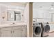 Well-lit laundry room and bathroom combo with modern washer and dryer at 7624 S Cove Cir, Centennial, CO 80122