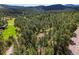 Aerial view shows a home nestled within a dense forest and rolling hills at 8422 S Ault Ln, Morrison, CO 80465