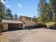 Charming home exterior features a modern garage door, neutral paint, and a wooded lot at 8422 S Ault Ln, Morrison, CO 80465