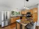 Well-lit kitchen boasts granite counters, stainless appliances, wood cabinets, and center island with bar stool seating at 8422 S Ault Ln, Morrison, CO 80465