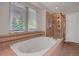 Bright bathroom featuring a large soaking tub, separate shower, and window at 13950 E Chenango Dr, Aurora, CO 80015