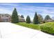 Manicured front yard features lush greenery, mature trees, and a welcoming driveway at 13950 E Chenango Dr, Aurora, CO 80015