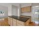 Kitchen island with black countertops, wood floors, and neutral-colored cabinetry at 13950 E Chenango Dr, Aurora, CO 80015