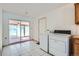 Laundry area with white appliances, tile flooring, and access to the enclosed sunroom, offering convenience at 2525 S Ivanhoe Pl, Denver, CO 80222