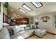 Well-lit living room features wood floors, a large sectional sofa, skylights, and easy access to the kitchen at 11883 W Marlowe Pl, Morrison, CO 80465