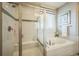 A modern bathroom showcasing a glass-enclosed shower, soaking tub, and elegant window with a striped valance at 1261 W 170Th Ave, Broomfield, CO 80023