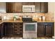 Well-equipped kitchen with stainless steel appliances, tile backsplash, and dark wood cabinetry at 5562 W 72Nd Pl, Westminster, CO 80003