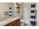 Well-lit bathroom features a double sink vanity with granite counters and a shower-tub with a stylish blue shower curtain at 15960 W 62Nd Dr, Arvada, CO 80403
