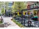 Charming outdoor seating area with black metal tables and chairs, bright yellow umbrellas, and views of the vibrant city street at 3330 E 4Th Ave, Denver, CO 80206