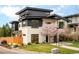 Modern two-story home with a black and white exterior, set back from the street with a well-manicured lawn and blooming tree at 99 S Albion St, Denver, CO 80246