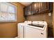 Functional laundry room with modern washer and dryer, dark cabinets, and a window for natural light at 9 Roder Gate Ln, Castle Pines, CO 80108