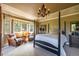 Comfortable main bedroom with a four-poster bed, chandelier, sitting area with leather chairs, and bright windows at 9 Roder Gate Ln, Castle Pines, CO 80108