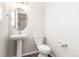 Clean half-bathroom with a pedestal sink, round mirror, and modern fixtures at 22921 E Union Ave, Aurora, CO 80015