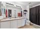 Bright bathroom featuring double sinks, white cabinets, a large mirror and a shower with black curtain at 178 Blue Bonnet Dr, Brighton, CO 80601