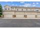 Townhome exterior with individual garages, stone accents, and neutral siding under a blue sky at 178 Blue Bonnet Dr, Brighton, CO 80601