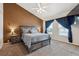 Comfortable bedroom featuring a bed with gray bedding, a ceiling fan and neutral carpeting at 178 Blue Bonnet Dr, Brighton, CO 80601