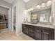 Well-lit bathroom with granite countertop, dual sinks, dark wood cabinets, and walk-in closet at 8056 Piney River Ave, Littleton, CO 80125