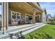 Inviting covered patio with comfortable seating, an outdoor grill, and a lush green lawn at 8056 Piney River Ave, Littleton, CO 80125