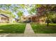Charming brick home featuring a covered front porch with lovely landscaping and healthy green lawn at 306 E Iowa Ave, Berthoud, CO 80513