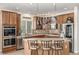 Well-lit kitchen features wood cabinetry, tiled countertops and backsplash, stainless appliances, and a central island with seating at 1335 Galactic Pl, Castle Rock, CO 80108