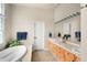 Well-lit bathroom featuring double sinks, a large mirror, and a soaking tub with tile surround at 7332 Woodglen Pl, Castle Pines, CO 80108