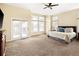 Bright main bedroom with carpet, ceiling fan, balcony access, and many windows at 7332 Woodglen Pl, Castle Pines, CO 80108
