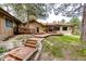 Inviting home exterior featuring a wooden deck, manicured lawn, and mature trees, creating a serene outdoor space at 8788 E Tanglewood Rd, Franktown, CO 80116