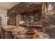 Granite countertop on bar area with stone archway, shelving, and seating for entertaining at 6302 Charrington Dr, Cherry Hills Village, CO 80111
